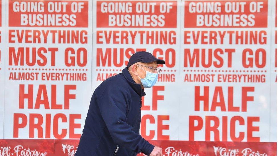 Man walks past shop closure sign