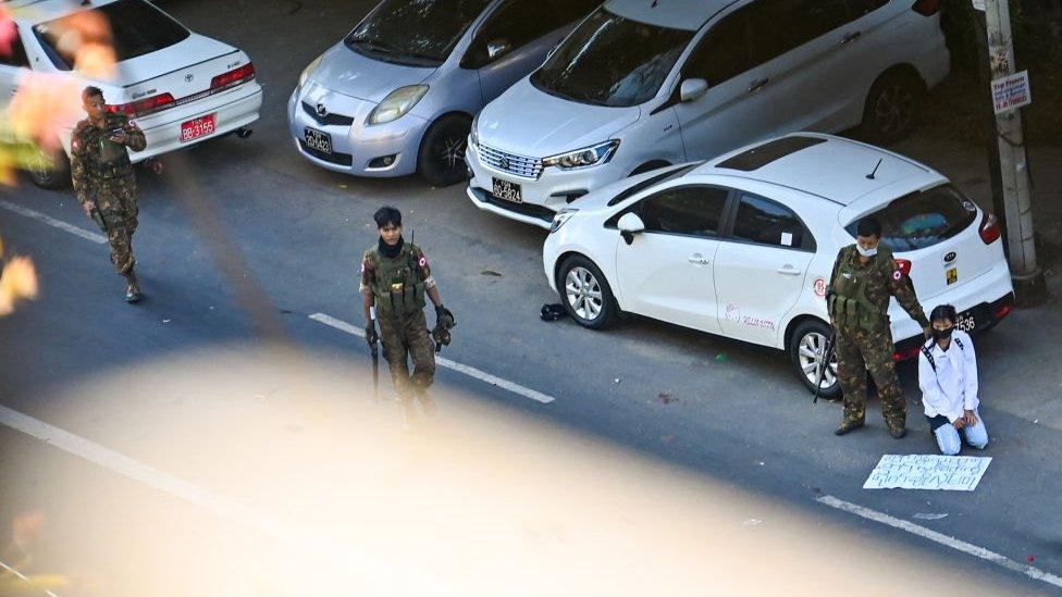 Image of soldiers detaining a main with sign