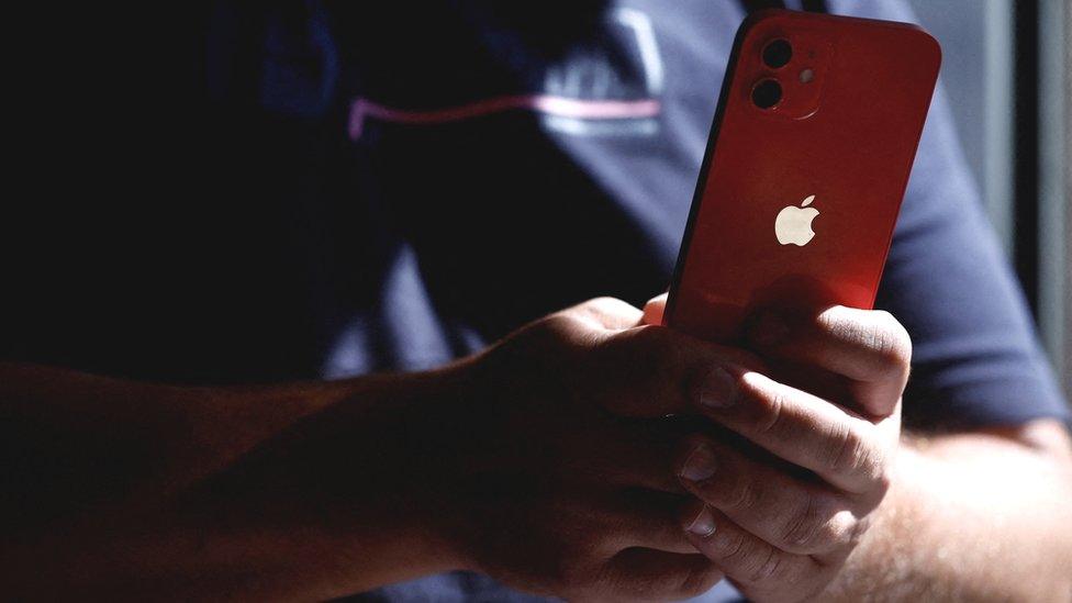 A man poses with an Apple iPhone 12 in a mobile phone store in Nantes, France