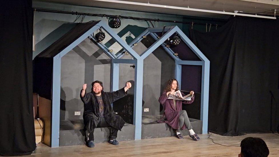 Jack and Jordan sitting in wooden booths pretending to read newspapers