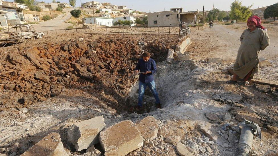 A Syrian man stands inside a crater caused by what activists said was a Russian air strike in Latamneh, Hama province (2 October 2015)