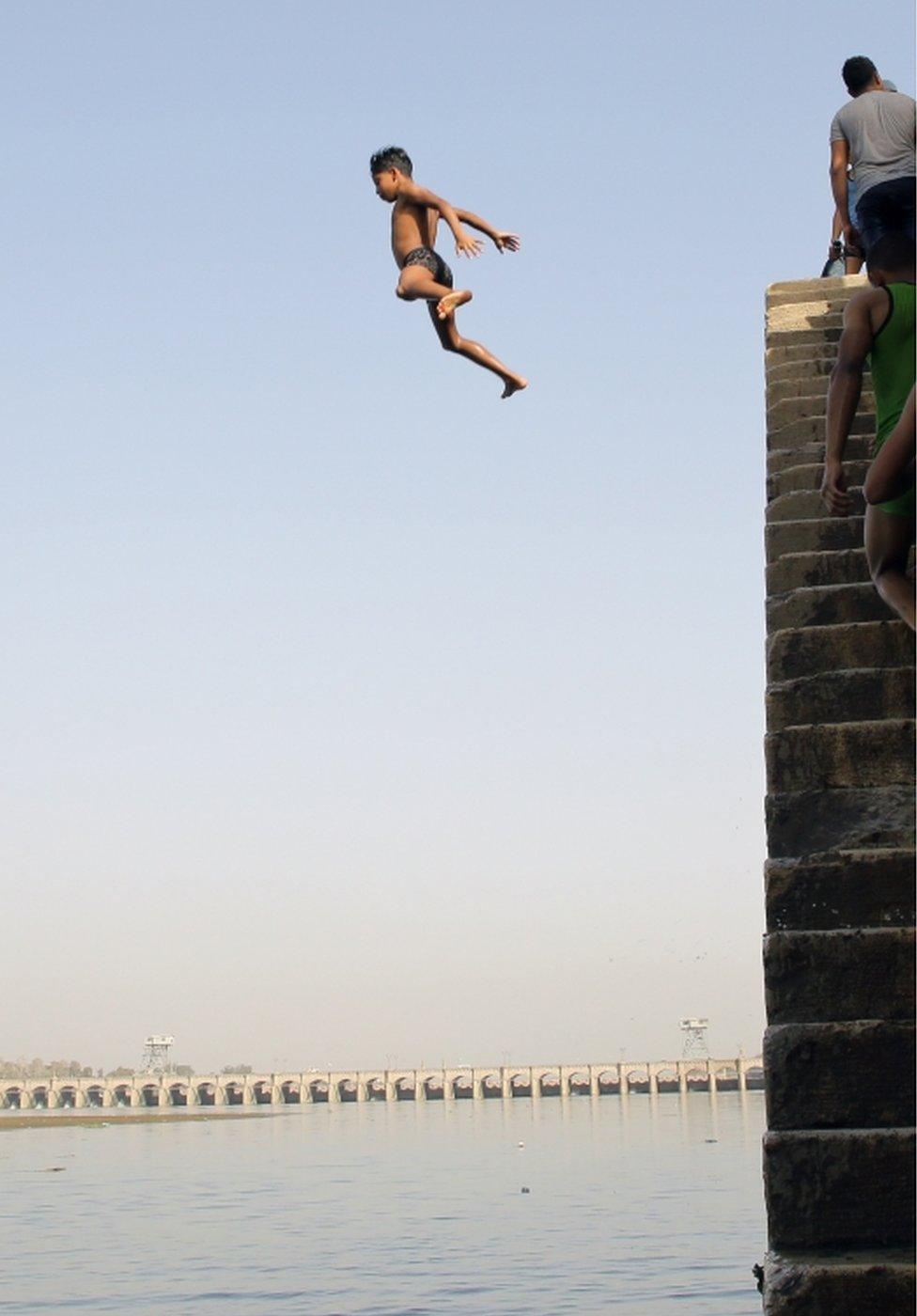 Children jump into the water of the Nile.