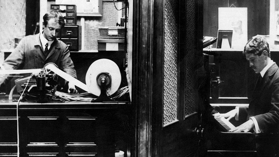 A pianist recording music onto a punched paper roll, for use on a player-piano