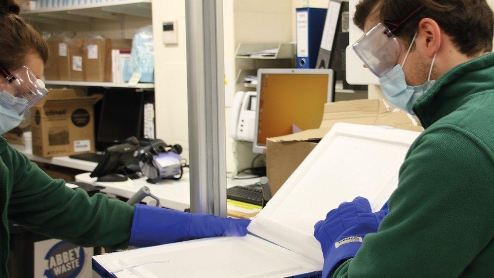 Lab workers open vaccine box