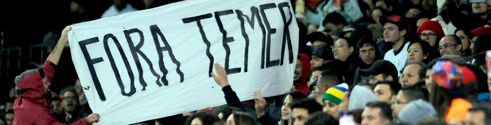 Fans at a football match hold a banner that reads Fora Temer - Portuguese for Temer Out