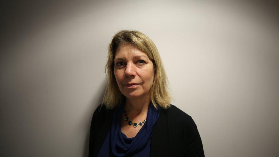 Dr Catherine White mid-shot standing with white wall behind her