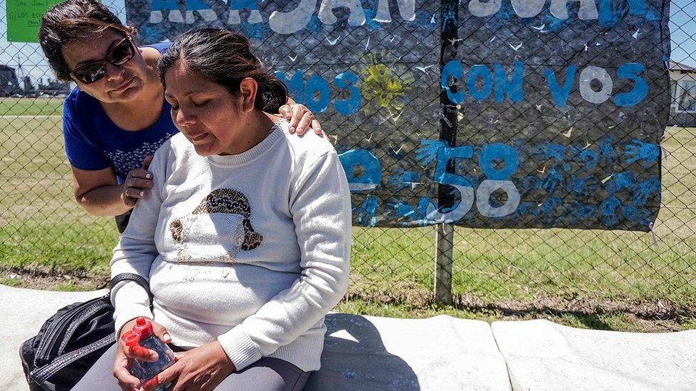 Elena Alfaro sitting and being comforted