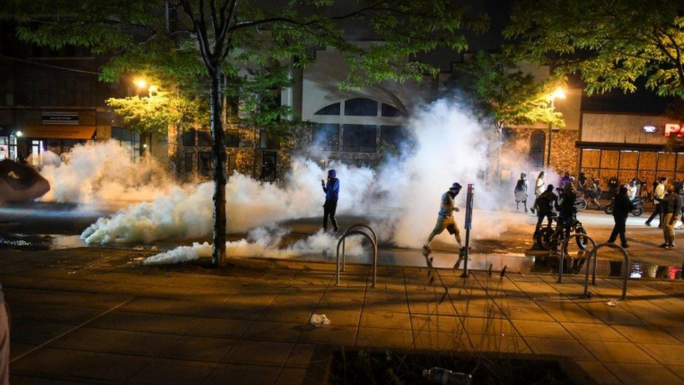 Protesters run from tear gas near the Minneapolis Police third precinct