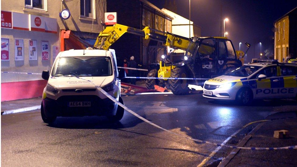 Police tape surrounds a JCB low loader outside Walsoken Post Office in Wisbech following a ram-raid