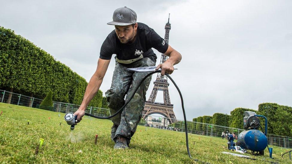 French artist Saype works on a monumental fresco on the Champ-de-Mars in Paris, France