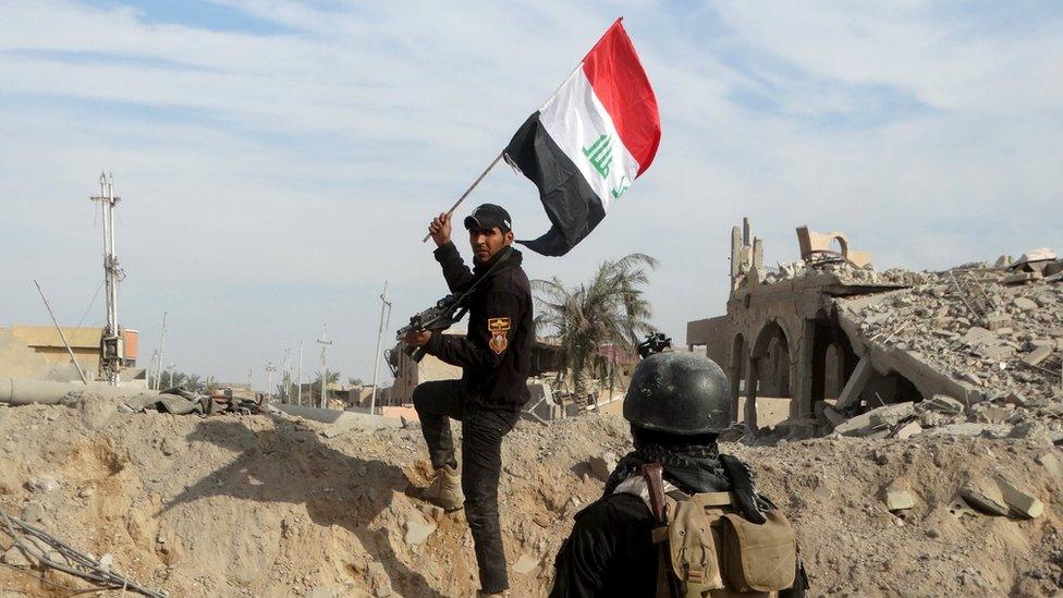 A member from the Iraqi security forces holds an Iraqi flag in the city of Ramadi, December 27, 2015.