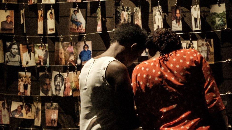 A picture taken on April 29, 2018 shows a visitors looking at victims' portraits at the Kigali Genocide Memorial in Kigali, Rwand