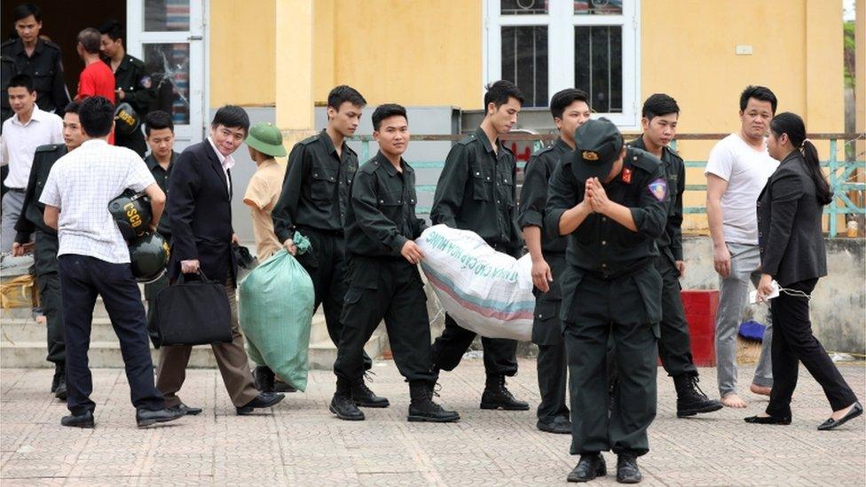 A police officer bows as he walks out of the Dong Tam commune on the outskirts of Hanoi, Vietnam, with 19 hostages who were originally held in a land dispute, 22 April 2017