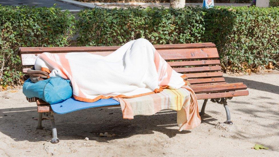 Homeless person sleeping on a bench