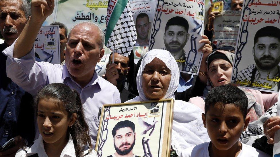 Palestinians hold posters in solidarity with Palestinians jailed in Israel at a protest in the West Bank city of Hebron (21 June 2018)