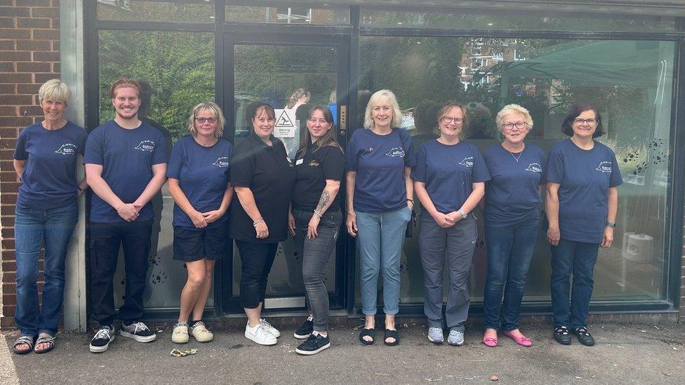 A group of people standing outside the rescue centre wearing blue matching t-shirts with a hedgehog logo on them