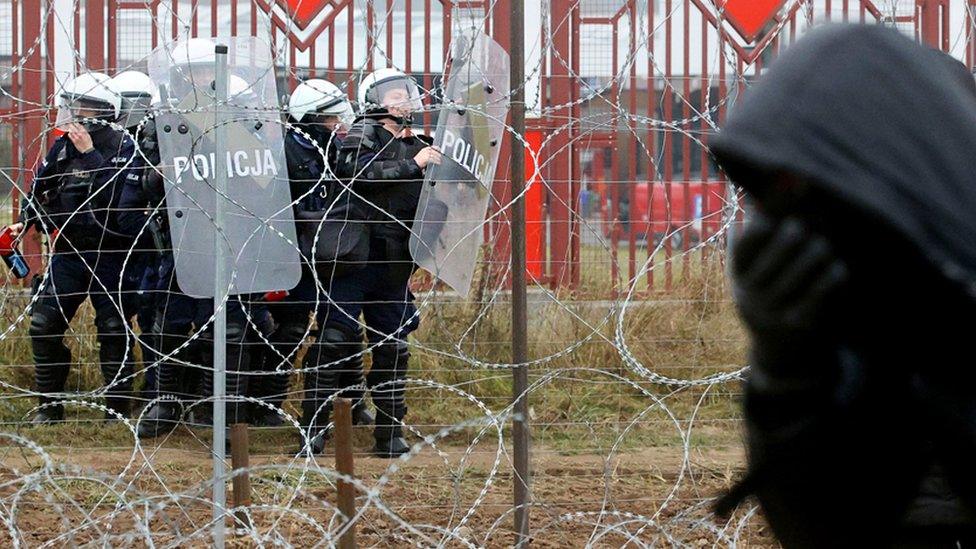 Polish police officers and a migrant is seen near the Bruzgi - Kuznica crossing point on the Belarusian-Polish border. 16 November 2021