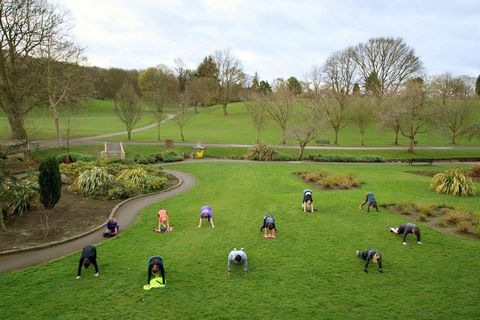 People exercise in a group class in a park