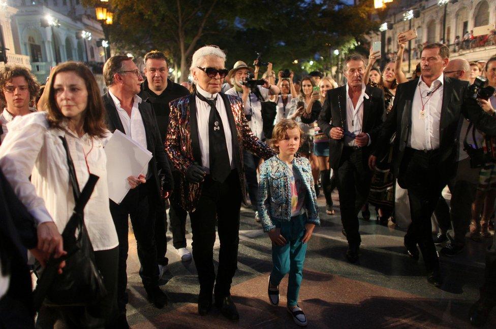 Karl Lagerfeld head designer and creative director of fashion house Chanel, walks with a model after a fashion show of his latest inter-seasonal Cruise collection, at the Paseo del Prado street in Havana, Cuba.