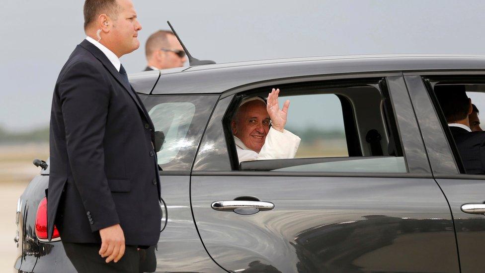 Pope Francis waves as he is driven away in a Fiat 500 model after arriving in the United States at Joint Base Andrews outside Washington on 22 September 2015