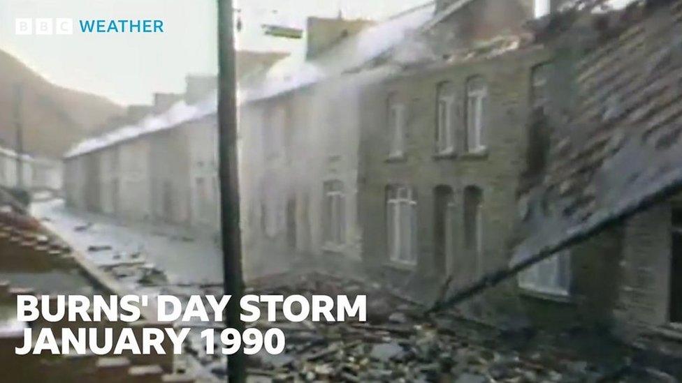 In a street of terraced houses, the roof from one is being blown into the street