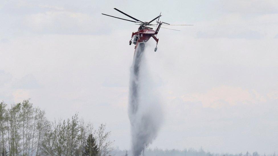 A helicopter tackles a huge wildfire in Canada