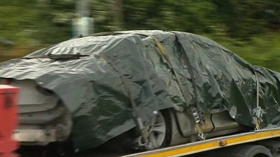 The burnt-out car being taken away on a lorry