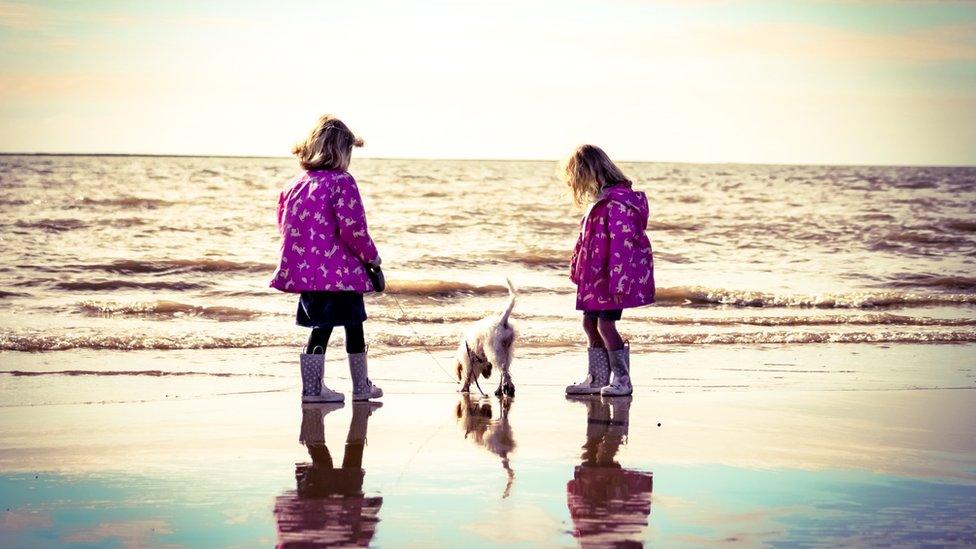 Two girls stand on beach at Ogmore on Sea with their puppy, Luna