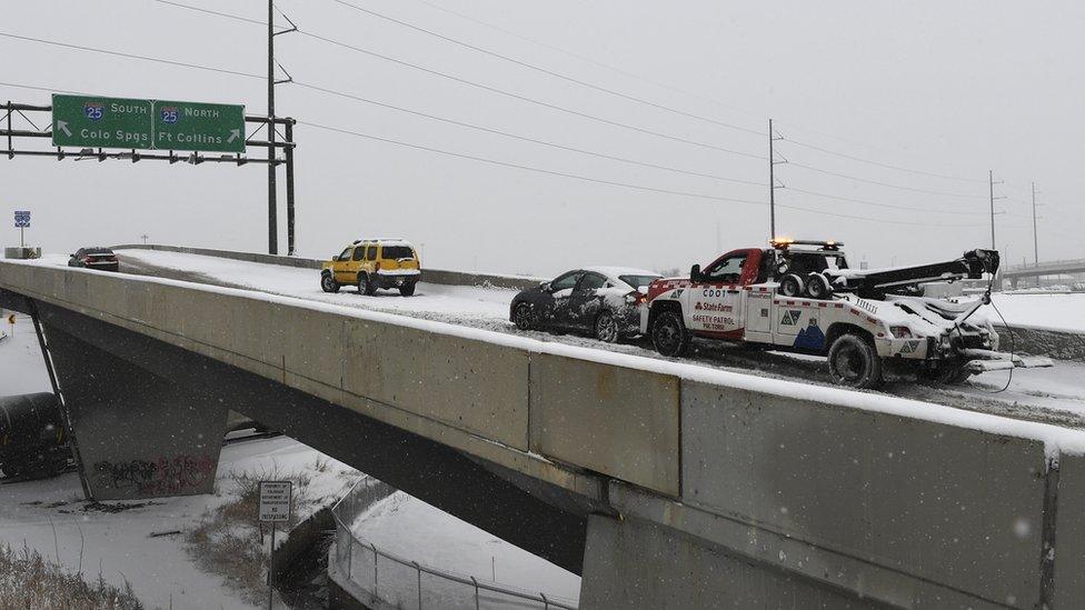 A tow truck pushes a car up the ramp in Denver