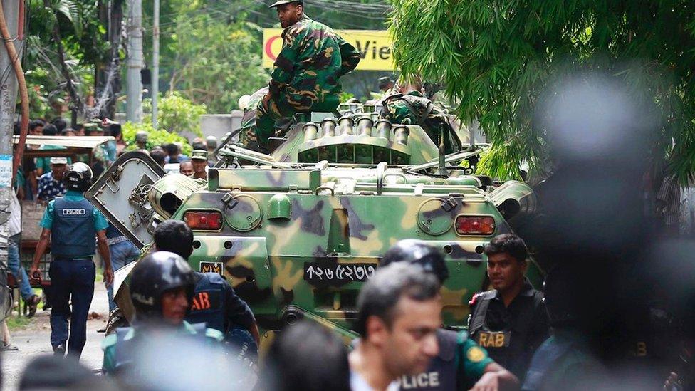 Bangladeshi soldiers and security personnel sit on top of armoured vehicles as they cordon off an area near a restaurant popular with foreigners after heavily armed militants took dozens of hostages, in a diplomatic zone of the Bangladeshi capital Dhaka, Bangladesh, Saturday, 2 July 2016.