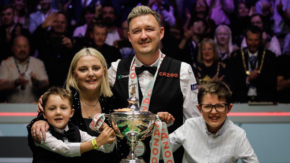 Kyren Wilson celebrates with his family in front of the World Championship trophy