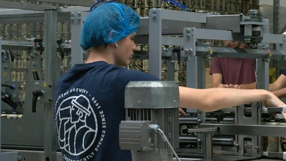 Woman packaging beer cans on a production line