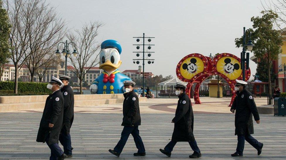 Staff workers wear protective masks in Shanghai Disneyland Park.