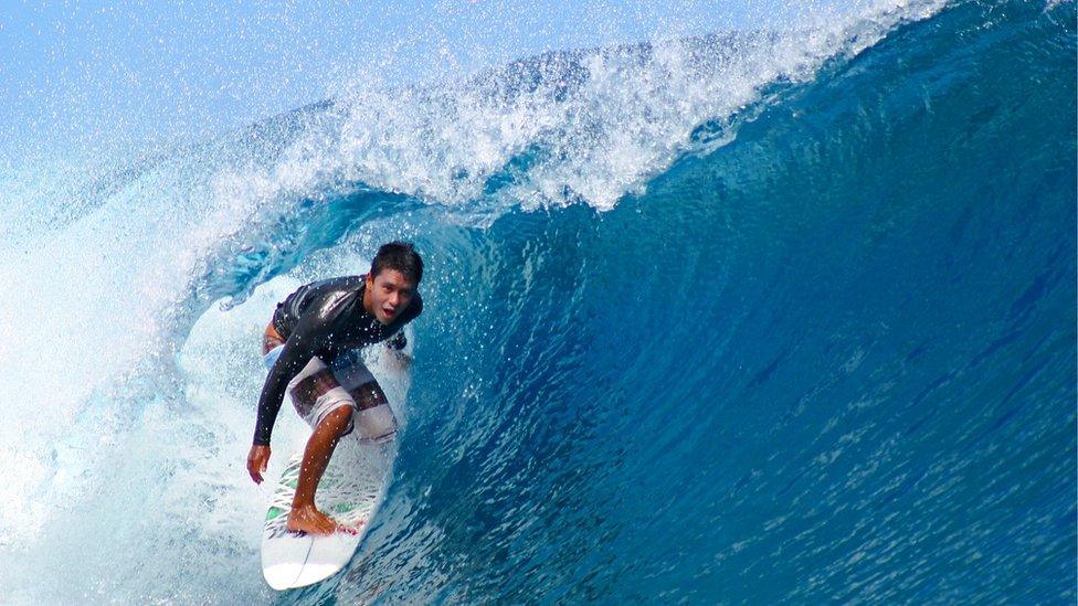 A young man surfs the waves in Teahupo'o, Tahiti