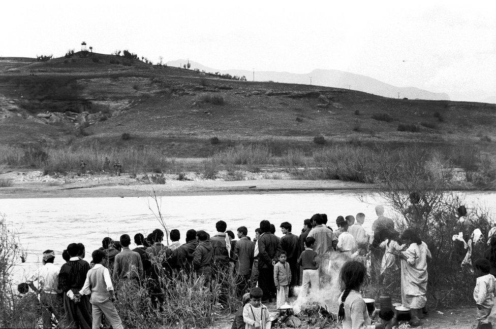 Kurdish people wait on the Iraq side of the Khabur River