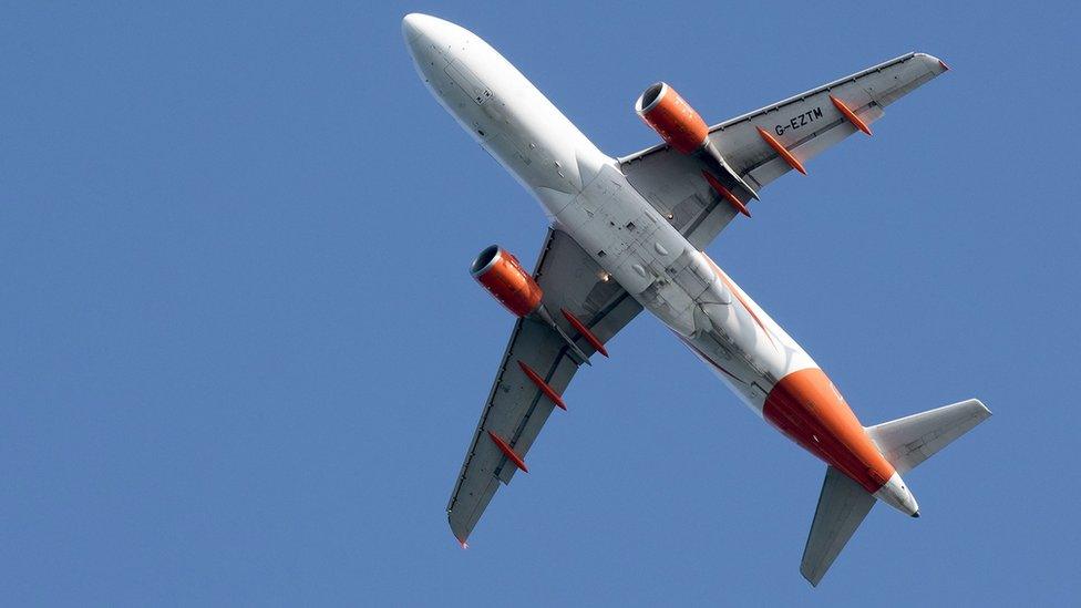 The underside of a passenger plane seen in the sky