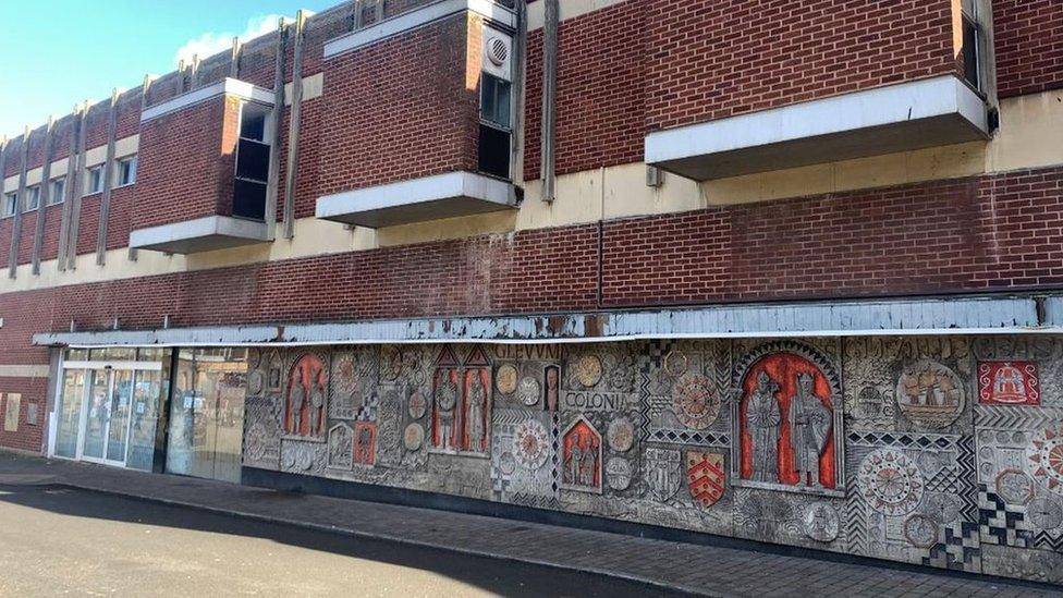 A stone mural on a derelict building