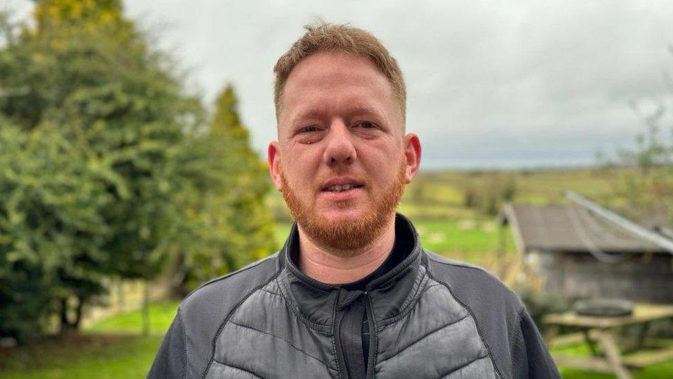 Man with ginger beard standing in front of trees