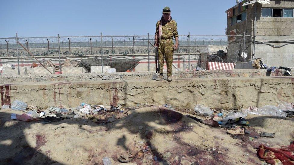 A Taliban fighter stands at the scene of the attack