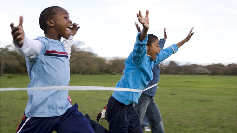 Boys running through finishing line - stock photo