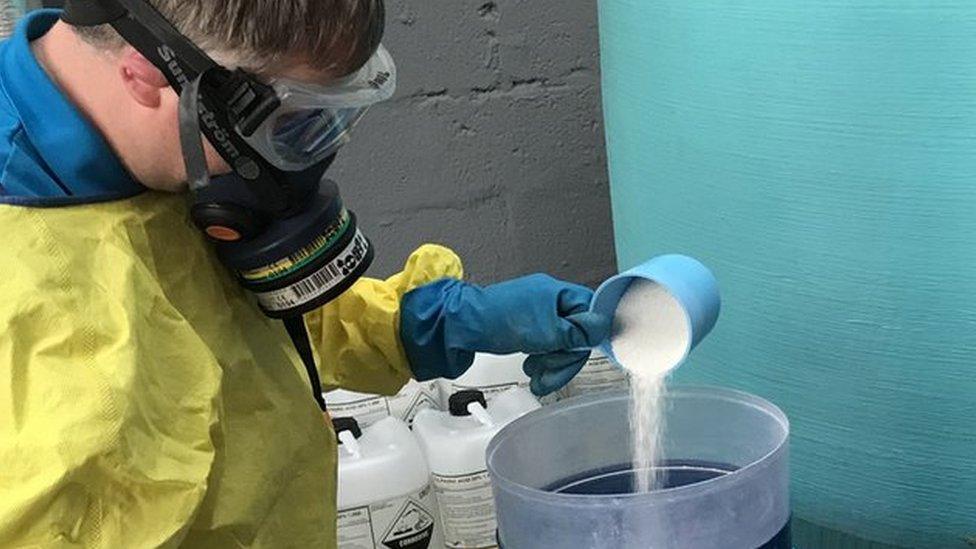 Phil Jameson pouring chlorine powder in the pool's chlorination machine