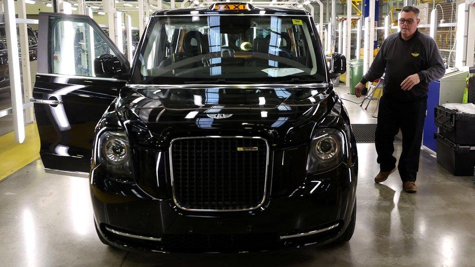 A worker walks along the TX electric taxi production line inside the London Electric Vehicle Company Factory in Coventry, Britain.