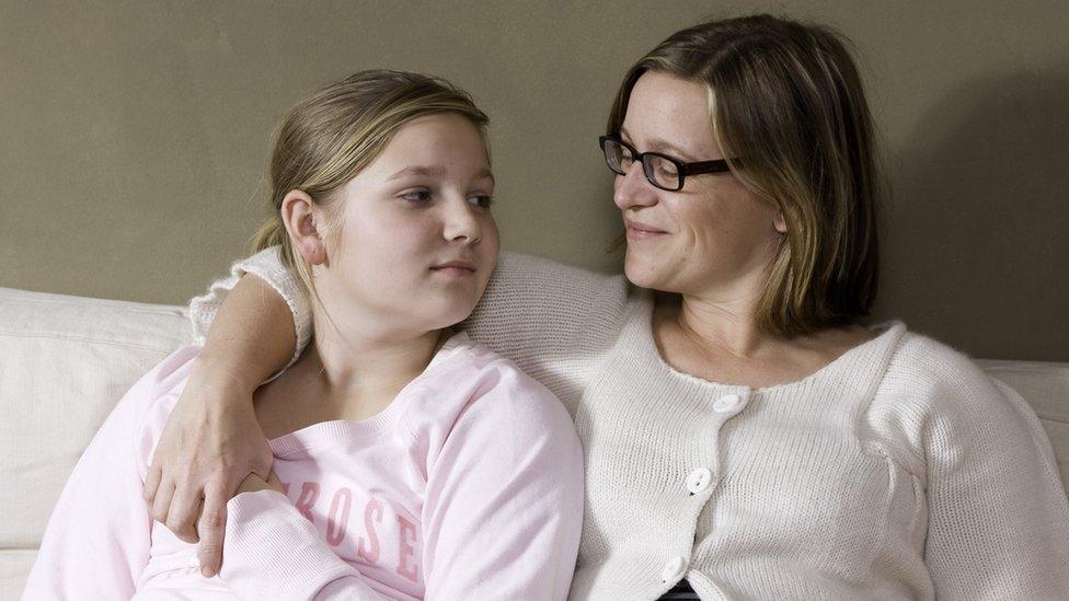 Mother and teenager daughter talking on a sofa