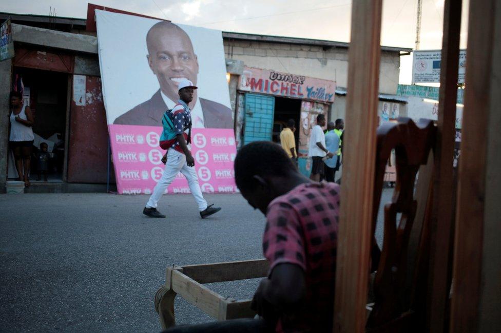 A man walks next to a billboard of presidential candidate Jovenel Moise in Port-au-Prince, Haiti, 17 November