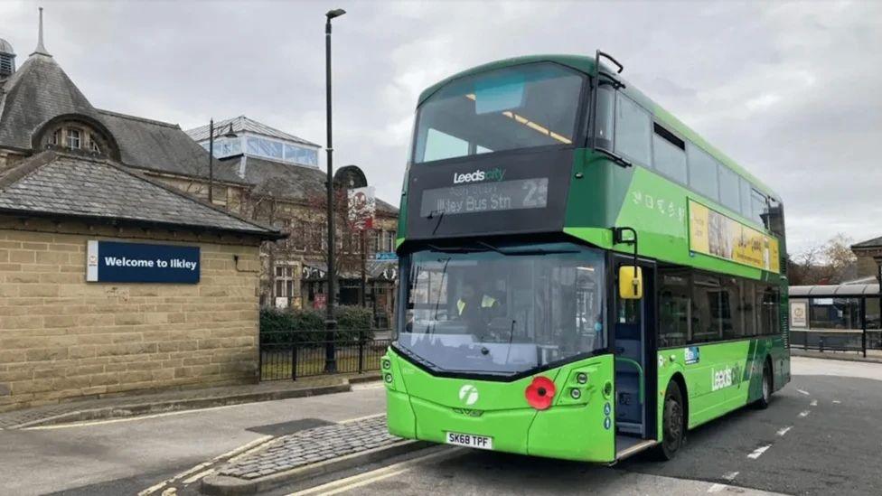 A bright green number 25 double-decker bus parked at Ilkley bus station