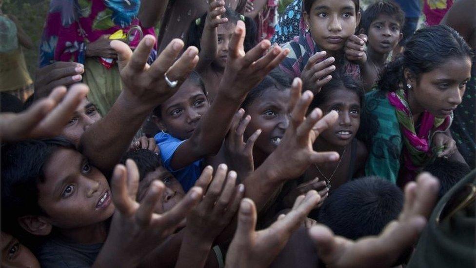 Flood affected children spread their hands to catch biscuits being distributed by a man in Morigaon district, east of Gauhati, northeastern Assam state, India, Sunday, July 31, 2016.