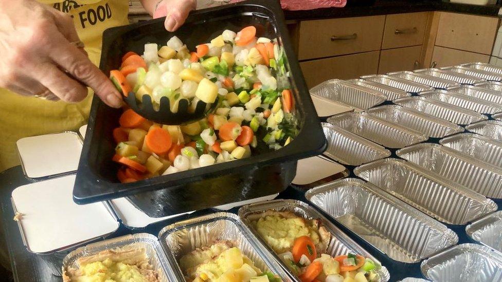 A container full of vegetables being portioned out.