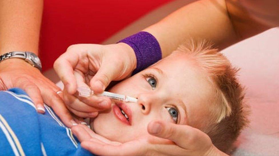 nasal flu vaccine given by a nurse to a four year old patient.