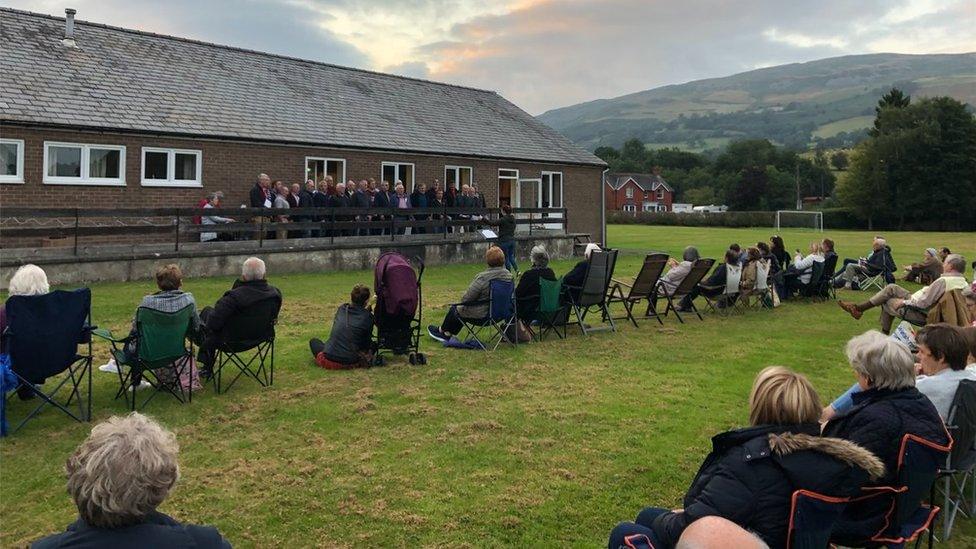 Pobl yn gwylio'r côr ar gae Ysgol Pennant