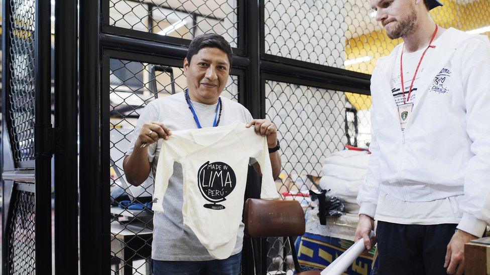 A prisoner holding up a finished shirt at San Pedro de Lurigancho prison